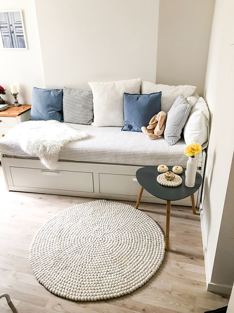 Na foto quarto infantil com cama e roupa de cama branca. Almofadas nas cores azul e branco decoram a cama. 