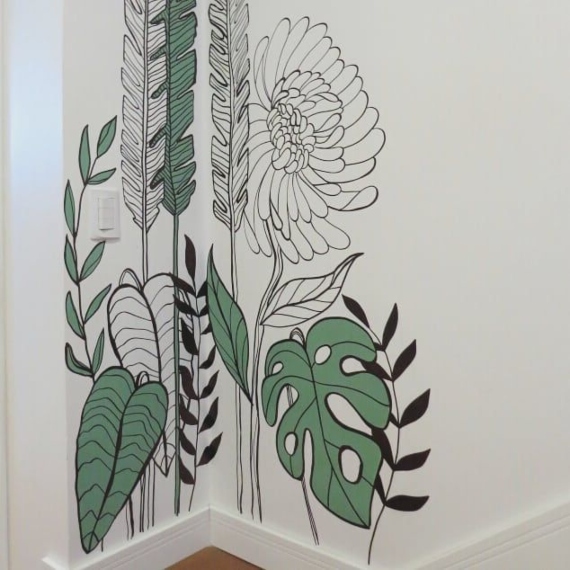 Pintura orgânica de folhas e flores feita na vertical e no encontro entre duas paredes